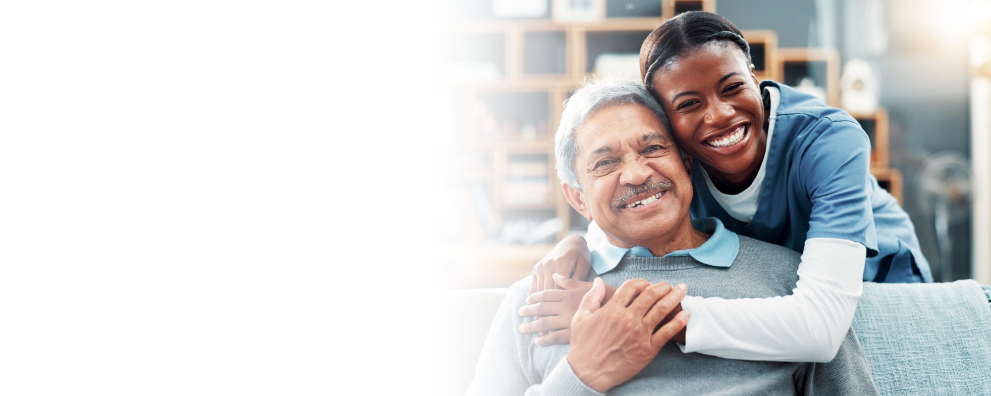 Caregiver and senior man smiling together on couch – Our Service Area Caregiver and senior man smiling together on couch - Our Service Area