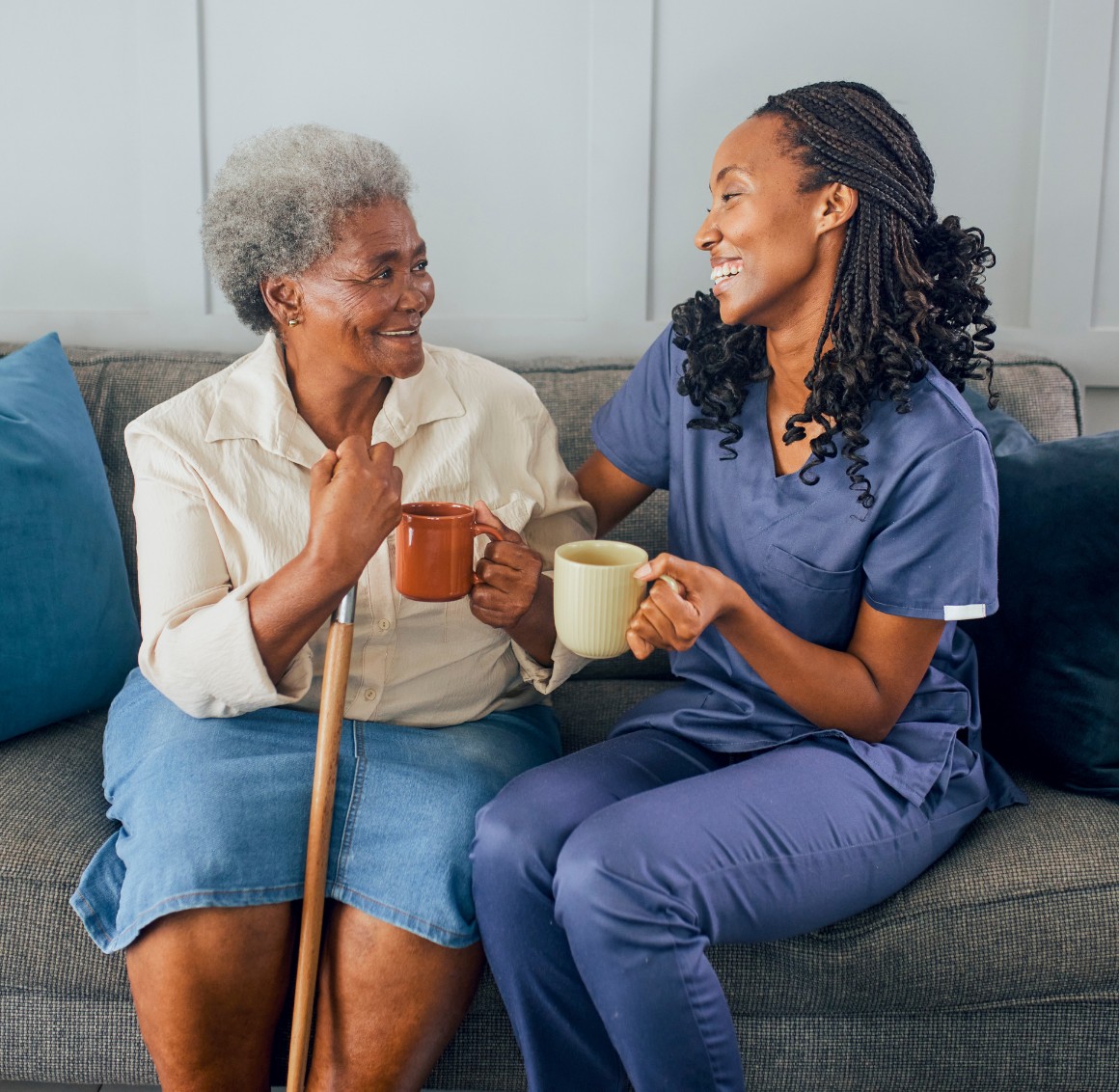 Caregiver and senior woman drinking coffee on couch Caregiver and senior woman drinking coffee on couch